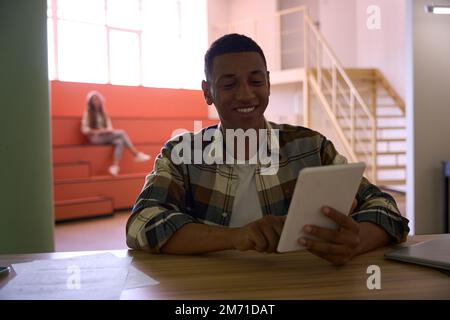 Happy African American guy is using tablet Stock Photo