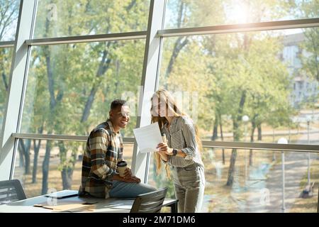 Smiling pretty lady showing documents to her male colleague Stock Photo