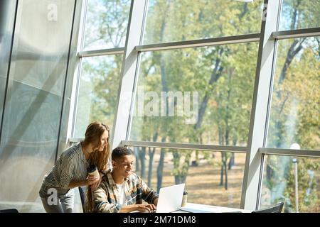 Happy coworkers working together while using laptop Stock Photo