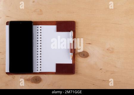 Digitalization concept. Paper notebook vs smartphone. Digital phone with blank black screen and empty  jotter  lie on wooden table. Copy space Stock Photo