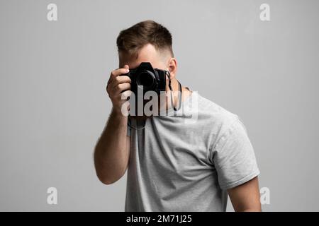 Professional bearded photographer holding a camera and ready to do a picture. Stock Photo