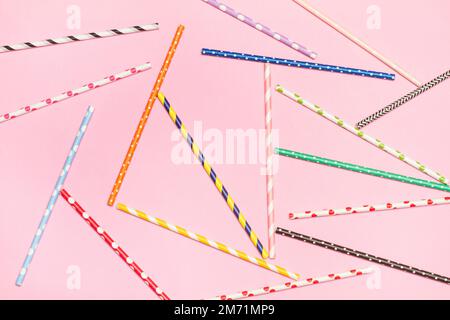 Colored with polka dots and striped drinking straws on a pink background with copy space Stock Photo