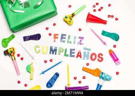 Happy birthday greeting card with a gift box, colored whistles and candles on a white background (Trad: Happy Birthday) Stock Photo