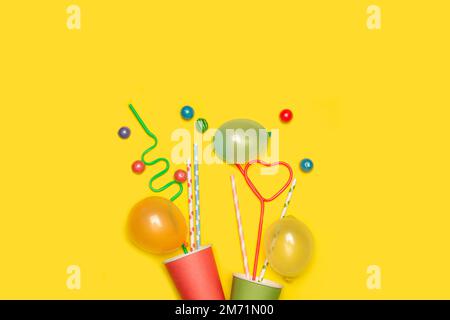 Greeting card with colored disposable cups with straws on a yellow background with copy space Stock Photo