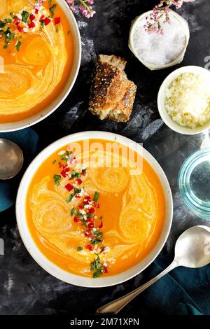 Red Lentil Piquillo Pepper Bisque in white bowls with blue napkins Stock Photo