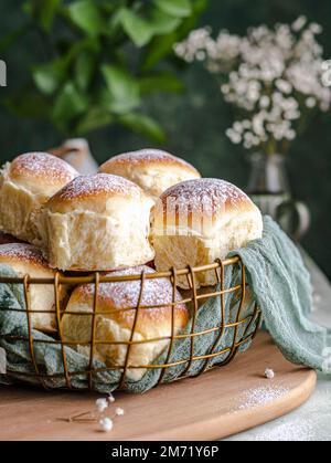 Homemade milk and creamcheese buns in a basket with a cloth next to a window Stock Photo