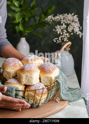 Homemade milk and creamcheese buns in a basket with a cloth next to a window Stock Photo