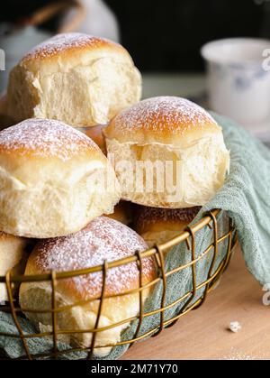 Homemade milk and creamcheese buns in a basket with a cloth next to a window Stock Photo