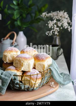 Homemade milk and creamcheese buns in a basket with a cloth next to a window Stock Photo