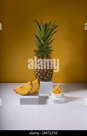 pineapple cocktail, with pineapple slice and a whole fresh pineapple on a yellow and white background, no people Stock Photo
