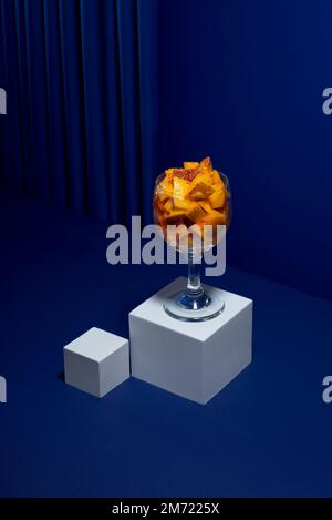 fresh cut mango cocktail with chili powder in a glass cup on a blue background, no people Stock Photo