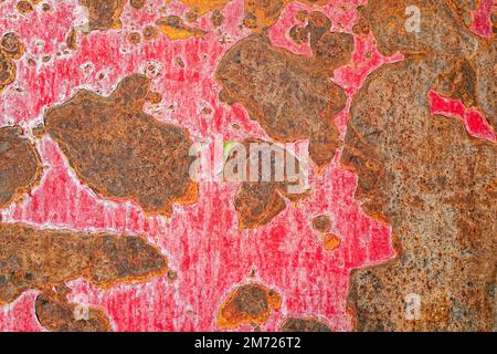 The red paint peeling from a rusty metal surface Stock Photo