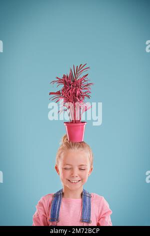 Maybe I can join the circus....a little girl holding a potplant on her head. Stock Photo