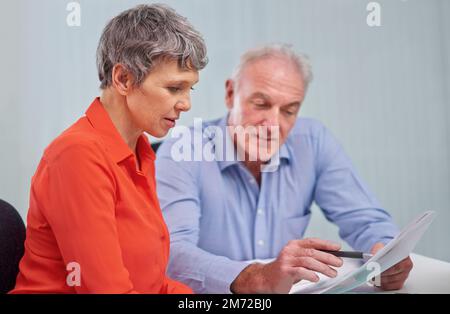 Going over a business proposal together. two mature business colleagues sitting at a desk discussing a document. Stock Photo