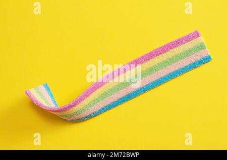 Colored strip of marmalade on yellow background close-up, top view. Jelly candies in sugar sprinkles Stock Photo