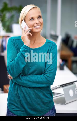 Sounds like things are looking up. an attractive young woman having a phone conversation at work. Stock Photo