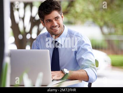 An pleasant escape from the office. A handsome young businessman working on his laptop outdoors. Stock Photo