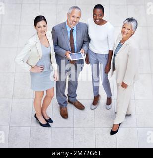 Dedicated to the companys success. HIgh angle portrait of a diverse and confident group of businesspeople standing with a digital tablet. Stock Photo