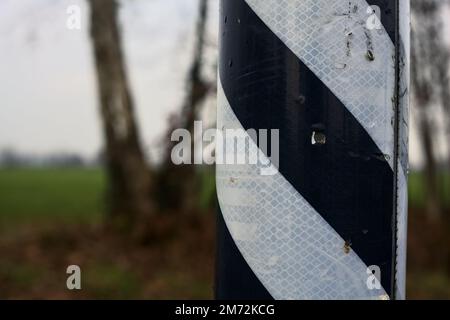 Black  and white texture on a pole with trees in the background seen up close Stock Photo