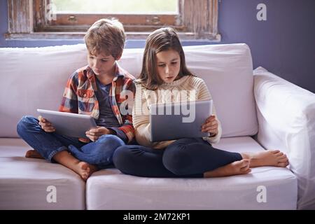 Siblings online. a young brother and sister using their digital tablets. Stock Photo