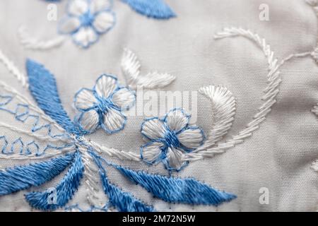 Macro abstract texture background of a blue and white needlepoint crafted flower pattern on white cloth Stock Photo