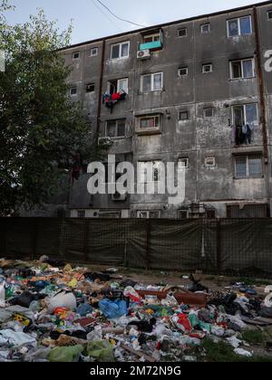 A vertical shot of a pile of garbage in front of old grungy apartment buildings in Ferentari Stock Photo