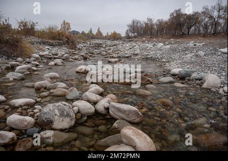 Slow and not deep mountain river with rounded stones Stock Photo