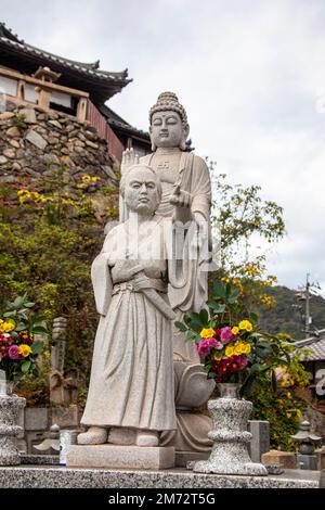 Fukuyama Japan 5th Dec 2022: the stone statue of Japanese samurai Sakamoto Ryoma and Buddha in front of temple Josenji Tomonoura. Stock Photo