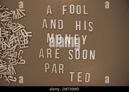 A FOOL AND HIS MONEY ARE SOON PARTED in wooden English words language ...