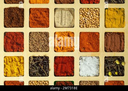 Close up of a colorful selection of spices portioned in square shaped spaces, top view backdrop Stock Photo