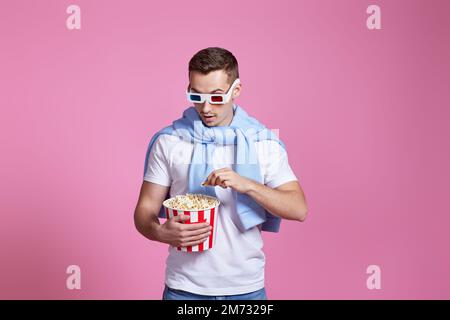 Young caucasian man in 3d glasses eating popcorn Stock Photo