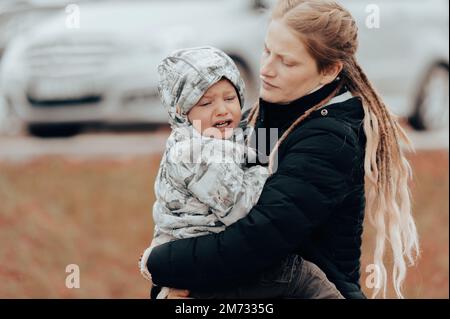 Mother holding crying baby, sad little boy being hugged by his mother Stock Photo