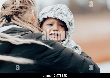 Mother holding crying baby, sad little boy being hugged by his mother Stock Photo