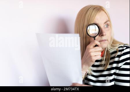 Woman looking through magnifying glass or loupe Stock Photo