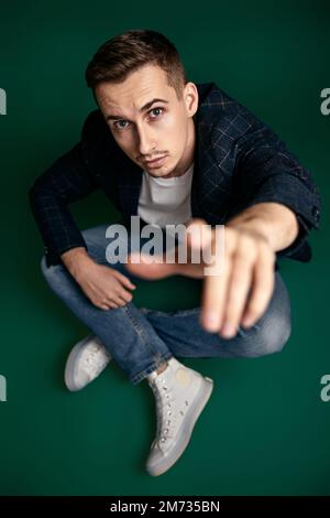 handsome man in plaid jacket sitting on the floor Stock Photo