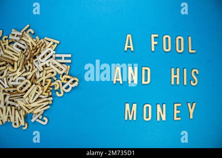 A FOOL AND HIS MONEY in wooden English language capital letters ...