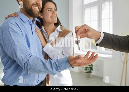 Happy young couple buy new house or apartment and take key from real estate agent Stock Photo