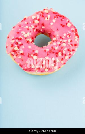 Pink sweet donut with pink sprinkles. Delicious glazed donut on blue background. Top view. Copy space Stock Photo