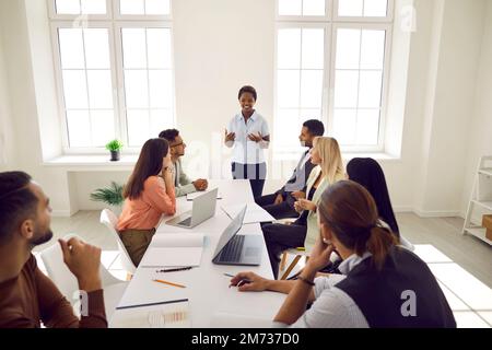 Young smart business woman speaking to colleagues talking about investment and market strategies. Stock Photo