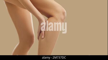 Young woman feeling sudden pain in her leg caused by a cramp or a calf muscle injury Stock Photo