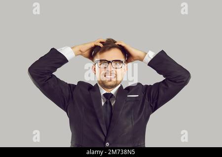 Young Caucasian man entrepreneur holding head with frightened look because of problems in business Stock Photo