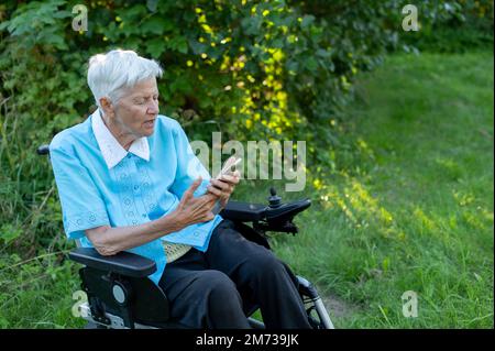 Elderly caucasian woman using mobile phone on wheelchair at the garden Stock Photo
