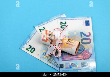 rolled into a roll of 50 euros on a light blue background of 20 euro banknotes. Stock Photo