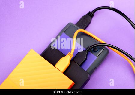 Multicolored external portable hard disk drives isolated on violet background Stock Photo