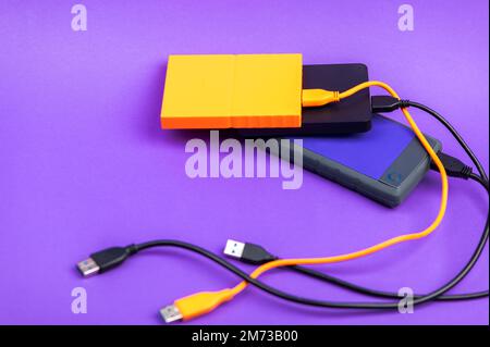 Multicolored external portable hard disk drives isolated on violet background Stock Photo