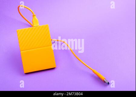 Orange color external portable hard disk drives isolated on light purple background Stock Photo