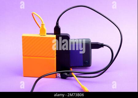Multicolored external portable hard disk drives isolated on violet background Stock Photo