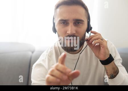 Head shot portrait of handsome smiling man wearing headset at office looking at camera. Call center introduction. Happy employee at workplace. People Stock Photo