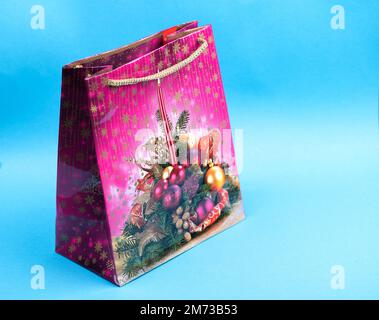 Colorful purple Christmas gift bag isolated on blue background Stock Photo