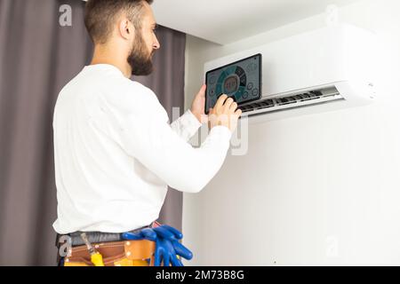 male technician service worker diagnosing for repairs air conditioner. person using tablet. Stock Photo